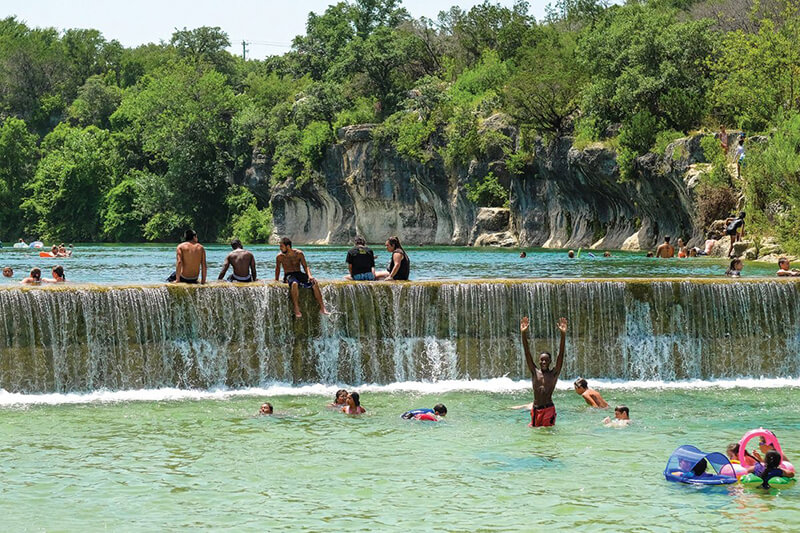 Diverse young crowd in colorful bathing suits swimming at Blue Hole Park on a summer day Diverse young crowd in colorful bathing suits swimming at Blue Hole Park on a summer day